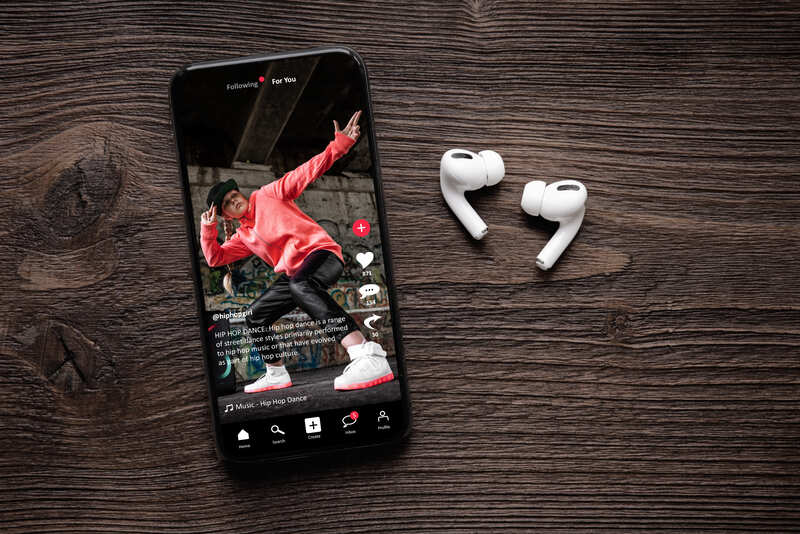 smartphone on a wooden table with white wireless headphones tiktok engagement
