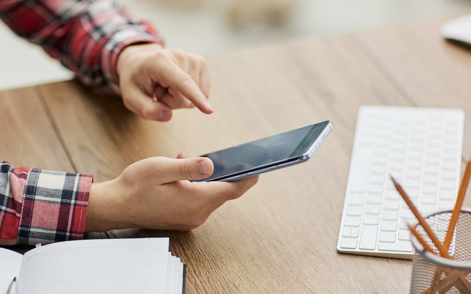 A person using a smartphone at a desk, illustrating mobile paid app promotion and app marketing strategy.