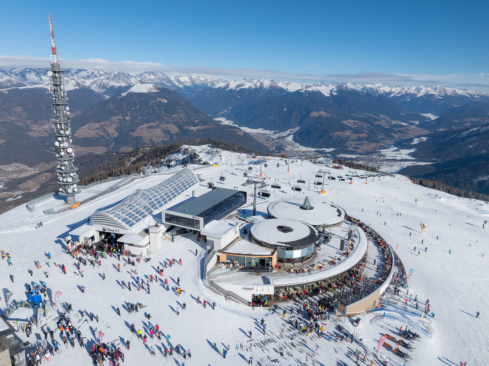 Kronplatz ski resort from the sky. Many people are around the resort enjoying the snow and nice sunny weather.