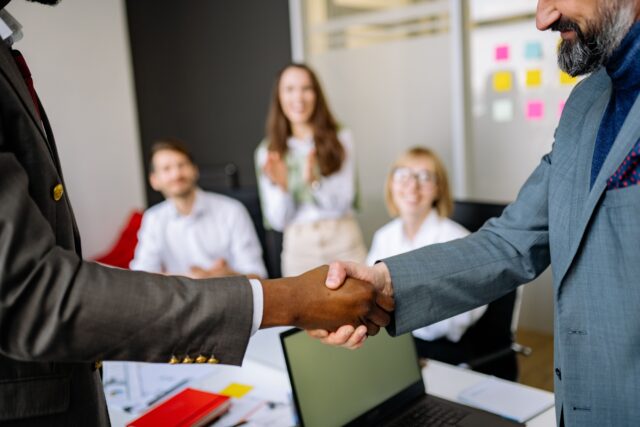 Business professionals shaking hands during a meeting as a symbol of customer trust and loyalty.