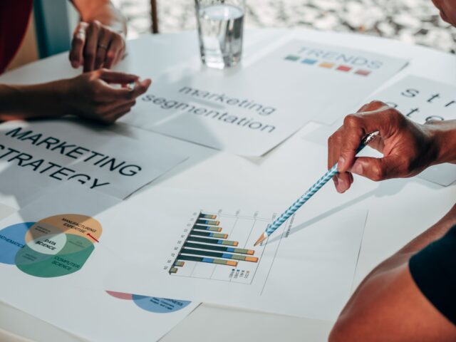 Business team reviewing marketing strategy documents and customer charts at a table.